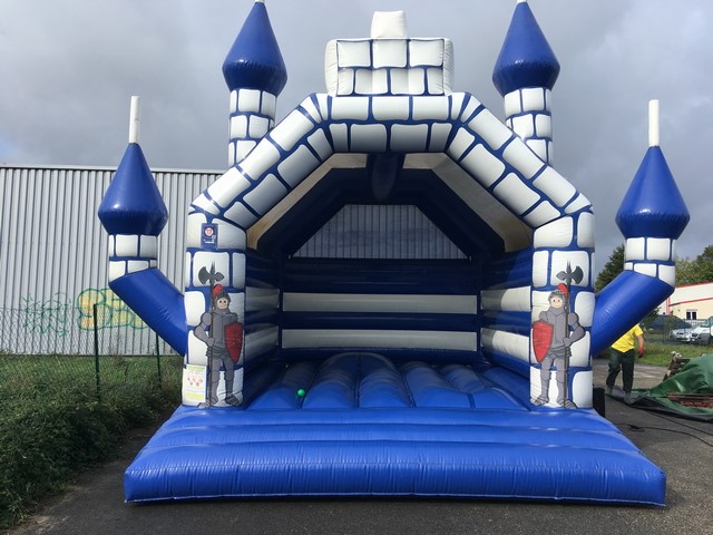 Château gonflable traditionnel multi-tours joliment décoré avec des chevaliers en armure.