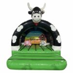 Château gonflable vache avec 2 obstacles de jeux et une bâche de toit.